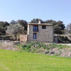 una vieja casa de piedra en un campo de hierba en Casa rural EL PAJAR DE TEJEDOR, en Mondot