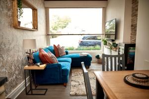 a living room with a blue couch and a window at Maltings Cottage in Barnard Castle