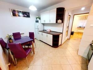 a kitchen and dining room with a table and purple chairs at Apartament Sprężynka in Mrągowo