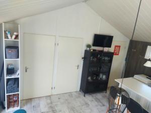 sala de estar con armarios blancos y TV en Cottage 322, en Dirkshorn