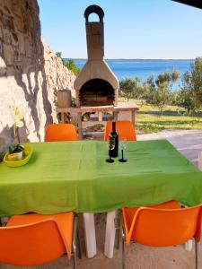 a green table with orange chairs and a fireplace at Apartments Mašić in Milovac