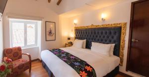 a bedroom with a large bed and a chair at Auka Boutique San Blas in Cusco