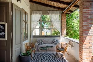 a porch with a couch and chairs and a window at Káli44 Vendégház in Révfülöp