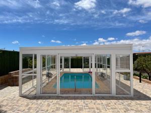a pool house with glass walls and a swimming pool at Villa El Cantil in Casillas de Morales
