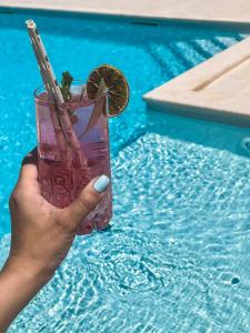 a hand holding a drink next to a swimming pool at Apartments Borghetto in Vinkuran