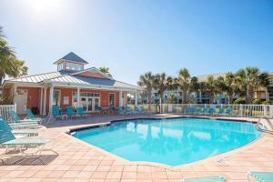 a swimming pool with blue chairs and a house at Seaside at Anastasia C101 in St. Augustine