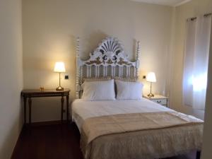 Bracara luxury guesthouse في براغا: غرفة نوم بسرير ابيض كبير ومصباحين