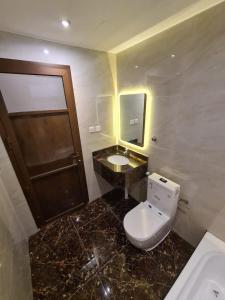 uma casa de banho com um WC, um lavatório e um espelho. em Rose Neri Lavender روز نيري الخزامى em Al Khobar