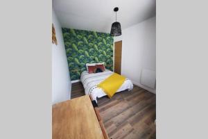 a bedroom with a bed with a yellow blanket at La Petite Maison Des Marais in Bourgneuf-en-Retz