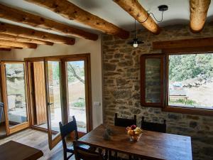 a dining room with a wooden table and windows at Casa rural EL PAJAR DE TEJEDOR in Mondot