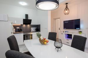 a kitchen with a white table with chairs and a television at Apartments Sole in Rab