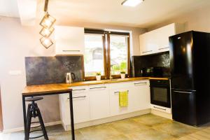 a kitchen with white cabinets and a black refrigerator at Sworne Zacisze in Swornegacie +13 photos