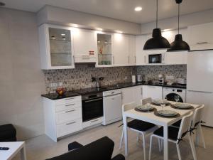 a kitchen with white cabinets and a table with chairs at Casinha D'Avó in Nazaré