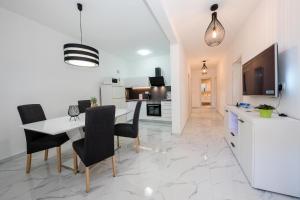 a kitchen and dining room with a white table and chairs at Apartments Sole in Rab