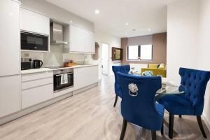 Luxustay Clyde House في ميلتون كينز: مطبخ وغرفة معيشة مع كراسي زرقاء وطاولة