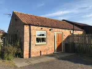 a brick house with a window and a fence at Little welham in Bedale