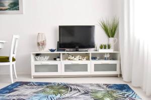 a living room with a tv on a white entertainment center at The Light House II, with rooftop and parking in Nazaré