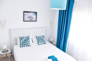a bedroom with a white bed and blue curtains at The Light House II, with rooftop and parking in Nazaré