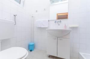 a white bathroom with a sink and a toilet at Apartments Zora in Starigrad-Paklenica