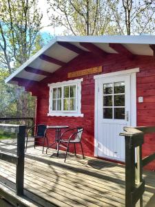 una cabina rossa con tavolo e sedie su una terrazza di Bakkakot 3 Cozy Cabin In The Woods ad Akureyri