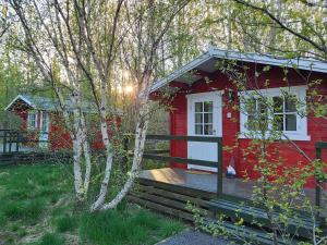 a red house with a porch and a deck at Bakkakot 3 Cozy Cabin In The Woods in Akureyri