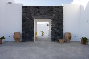 Cette chambre est dotée d'un mur en pierre et de vases. dans l'établissement Oia Kissiri - private pool villas, à Oia