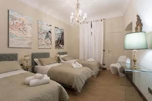 Habitación con 3 camas y lámpara de araña. en B&B Palazzo de I Mysteri, en Campobasso