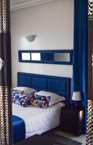 a bedroom with a blue bed with pillows and a mirror at Auberge Oualidia Dream in Oualidia