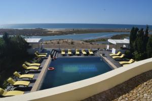 a swimming pool with lounge chairs and the ocean at Auberge Oualidia Dream in Oualidia