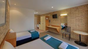 a room with a bedroom with a bed and a desk at Mulga Country Motor Inn in Charleville