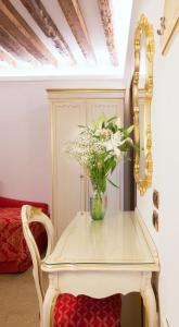 a white table with a vase of flowers on it at Hotel Leonardo in Venice