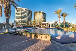 a large swimming pool with palm trees and buildings at Luna Blanca Two Bedroom Unit by Kivoya in Puerto Peñasco