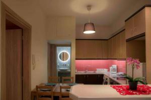 uma cozinha com uma mesa e uma cozinha com paredes cor-de-rosa em 7 Steps Apartment Metro Syggrou Fix near Acropolis em Atenas