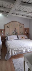 オルビアにあるMansarda Danielaの白いベッド1台(木製ヘッドボード付)が備わるベッドルーム1室が備わります。