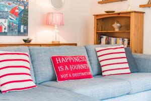 um sofá azul com duas almofadas vermelhas e brancas em The Landing em Hythe