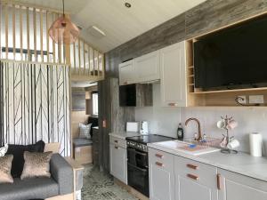 a kitchen with white cabinets and a couch in a room at Inverness Lodge-Sleeps 4-Parking-15 min to centre in Inverness