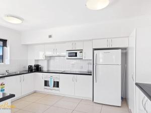 a kitchen with white cabinets and a refrigerator at Breakwater Apartment 402 in Shoal Bay