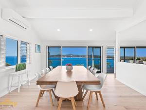 a dining room with a wooden table and white chairs at Randall Drive No 64 in Salamander Bay