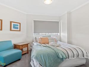 a bedroom with a bed and a blue chair at Breakwater Apartment 205 in Shoal Bay +13 photos