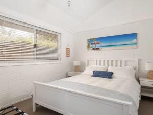 a white bedroom with a bed and a window at Little Kingsley Beach House in Boat Harbour