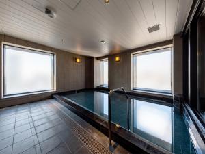 a swimming pool in a room with two windows at Granbell Hotel Osaka in Osaka