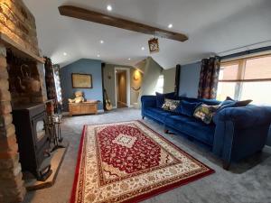 a living room with a blue couch and a fireplace at Stable cottage cozy,quirky with a hot tub in Bridlington