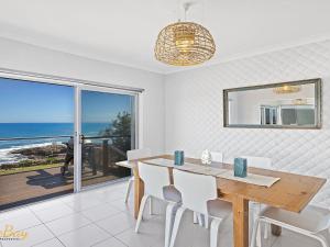 a dining room with a table and a view of the ocean at Elanora Ocean St No 8 in Anna Bay