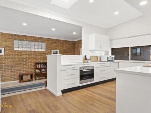 a kitchen with white cabinets and a brick wall at Blue Fish 41 Boulder Bay Road in Fingal Bay +15 photos