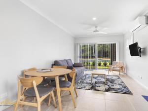 una sala de estar con una mesa y un sofá en Scott Street Couples Getaway, en Anna Bay