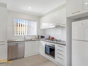 Una cocina blanca con estufa y refrigerador. en Scott Street Couples Getaway, en Anna Bay