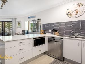a kitchen with white cabinets and stainless steel appliances at Karinya at Little Beach Downstairs in Nelson Bay