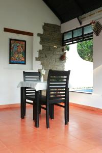 una mesa con dos sillas negras y una mesa y una mesa y una mesa en Mayas Beach House, en Mararikulam