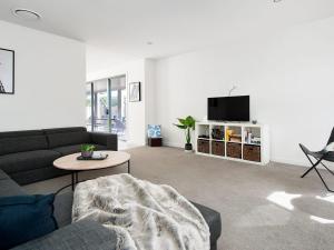 a living room with a couch and a tv at Forever Fingal 205 Rocky Point in Fingal Bay