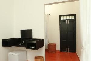 a room with a black door and a television at Mayas Beach House in Mararikulam